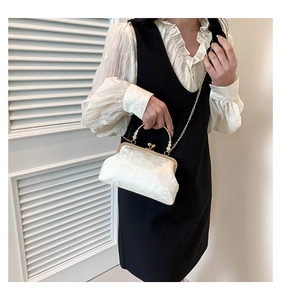 Detail of white floral jacquard clasp handbag with pearl handle and gold metal frame