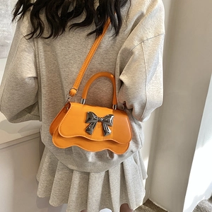 Fashionable orange shoulder bag with a silver bow and wave-shaped bottom edge