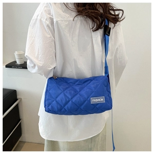 Blue quilted puffer crossbody bag with adjustable strap and fashion tag detail