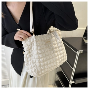 Detalle del bolso tote blanco con textura de burbujas, aro dorado y etiqueta moda