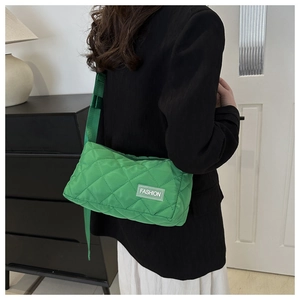 Detailed side view of quilted green crossbody tote bag with fashion label and strap