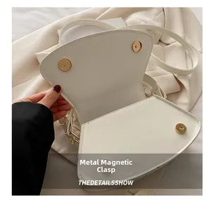 Details von drei goldenen Magnetverschlüssen an einer weißen Leder-Umhängetasche