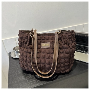 Detalle del bolso tote marrón oscuro con textura de burbujas y parche de cuero