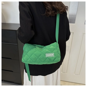 Detail of green quilted crossbody bag showing fashion label and diamond stitching texture
