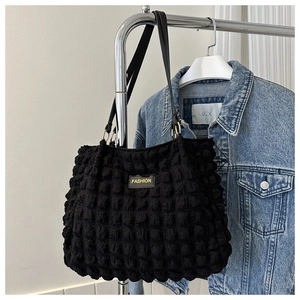 Detail of black bubble texture tote bag with golden metal rings and fashion leather tag