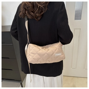 Detail view of beige quilted crossbody bag with FASHION label on a model shoulder