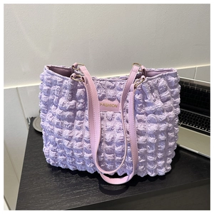 Vista macro del bolso tote lila con textura de burbujas y placa de metal dorada