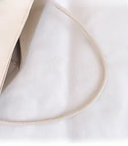Detailopname van de beige emmertas schouderband met versterkte stiksels en canvas patchwork