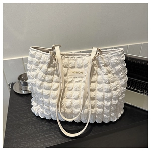 Detalle de bolso tote blanco acolchado con placa Fashion sobre un escritorio