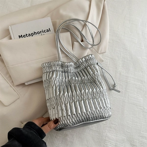 Silver pleated bucket bag with metallic drawstring design and leather shoulder straps