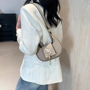 Beige faux leather hobo bag with gold SS hardware and tassel shown on model shoulder