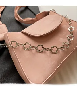 Detailed close-up of pink shoulder bag featuring clover-shaped silver chain and woven strap