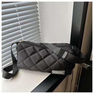Close-up of black quilted rhombus pattern fabric and fashion woven label on crossbody bag