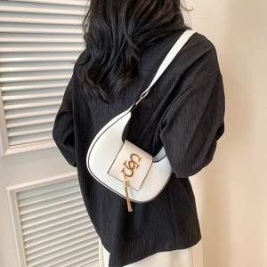 Minimalist white crescent hobo bag with gold hardware and tassel on model's shoulder