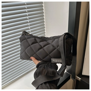 Detail of a black quilted tote bag featuring a decorative FASHION label and zip closure