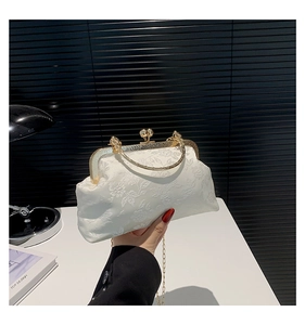 Close-up of white floral embossed handbag with golden dragon clasp and vintage handle