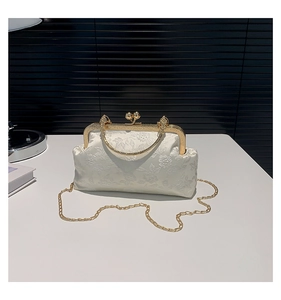 Detail of white floral embroidery bag with vintage gold clasp and round metal handle