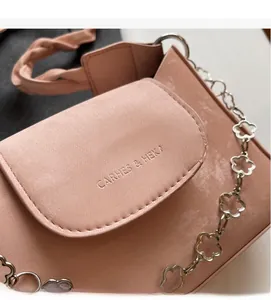 Detail of pink leather handbag featuring floral silver chain and woven handle