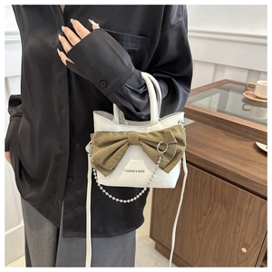 Mini sac blanc avec grand nœud marron et bandoulière chaîne porté par un mannequin