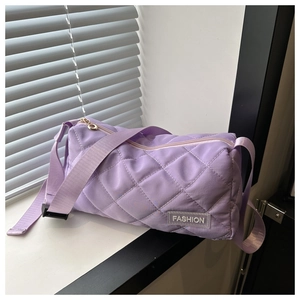 Detail of purple quilted shoulder bag with diamond stitching and round gold zipper pull