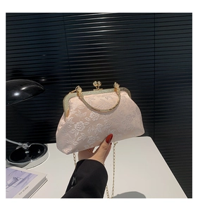 Detail of apricot pink silk clutch with white floral embroidery and gold metal handle