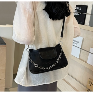 Detail of black crossbody bag featuring a silver flower chain and matte finish