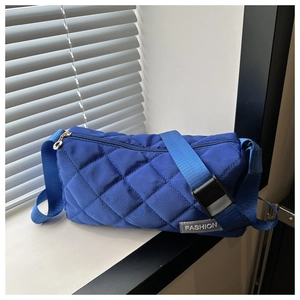 Close-up of blue quilted crossbody bag with adjustable wide strap and fashion label