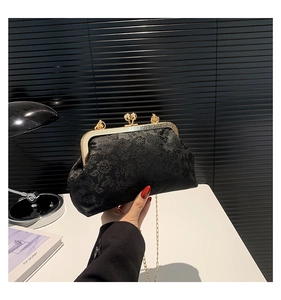 Detailed macro view of vintage black jacquard handbag with gold kiss lock closure