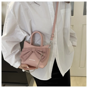 Détail du sac à main rose avec nœud papillon, chaîne argentée et texte mode chic