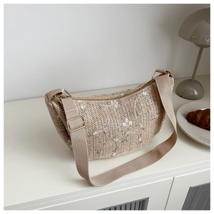 Detail of woven crescent bag with floral embroidery and adjustable canvas shoulder strap