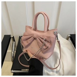Gros plan du sac rose avec nœud élégant, chaîne à perles argentées et logo mode
