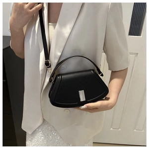 Details einer minimalistischen schwarzen PU-Schultertasche mit silberner Schnalle am Modell