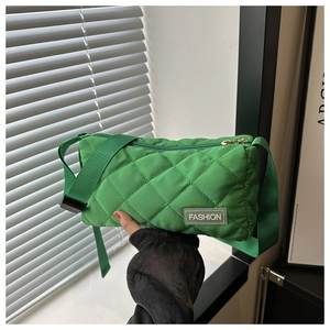 Detail of green quilted crossbody bag showing rhombus stitching and fashion label