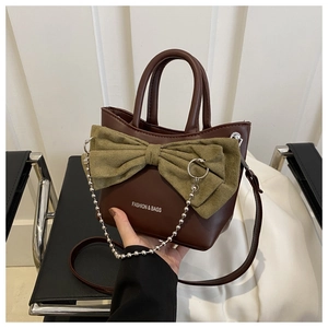 Détail du sac à bandoulière vintage marron avec nœud vert et chaîne en perles