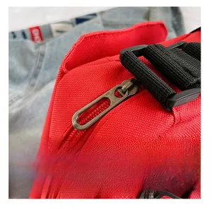 Detailed macro view of smooth metal zipper and black strap on a red canvas shoulder bag
