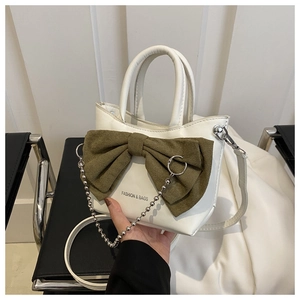 Détail du sac en cuir blanc avec grand nœud en daim vert olive et chaîne argentée
