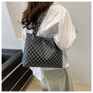 Detailed view of large black tote bag with white geometric chain pattern on female model