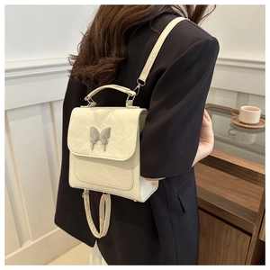 Detail of a creamy butterfly buckle mini backpack with wrinkled PU leather texture