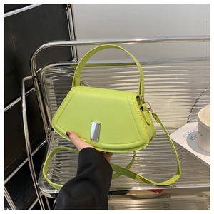 Detail der neongrünen Trapez-Handtasche mit silberner Metallschnalle auf Stahlregal