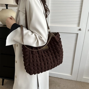 Bolso tote marrón con textura de burbujas, detalles dorados y etiqueta de moda