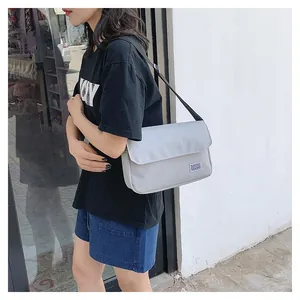 Detailed side view of the light gray water-repellent nylon crossbody bag with black strap