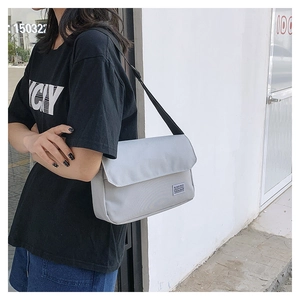 Detailed view of light grey nylon messenger bag with adjustable strap and flap closure