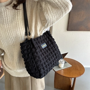 Bolso tote negro con textura de burbujas y etiqueta FASHION en un entorno de café