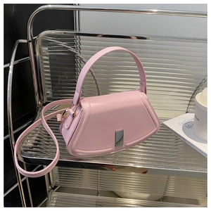 Detailansicht einer rosa Leder-Trapeztasche mit Metallschnalle auf einem Glasregal