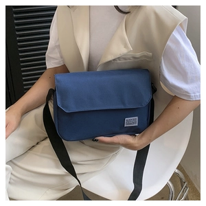 Detail of navy blue messenger bag with adjustable strap and minimalist brand label