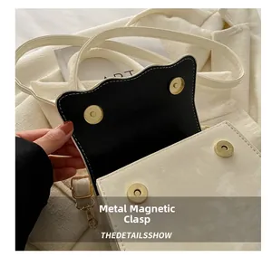 Close-up of golden magnetic hardware clasp on cream leather mini crossbody bag