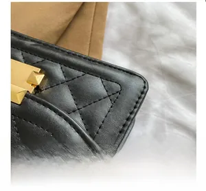 Close-up of black quilted leather bag featuring a gold rectangular buckle and stitch detail