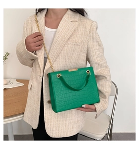 Chic green crocodile pattern handbag with gold chain strap on a blazer outfit