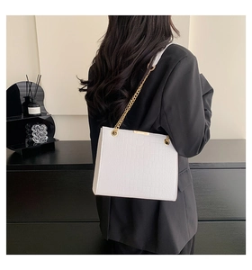 White crocodile embossed leather shoulder bag with gold chain strap on a model