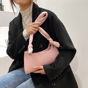 Pink crocodile-textured underarm bag with knot strap and golden metal ring details
